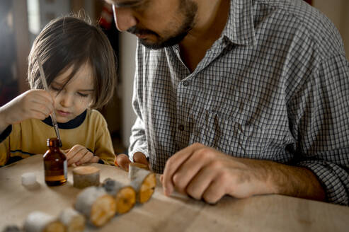 Vater und Sohn stellen zu Hause Holzspielzeug her - ANAF00448