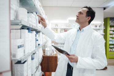 Pharmacist examining medicines through tablet PC at store - JOSEF14602