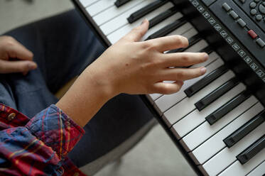 Hand of boy playing synthesizer at home - ANAF00453