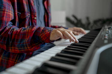 Boy playing and learning synthesizer at home - ANAF00455