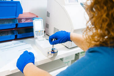 Ältere Krankenschwester bei der Analyse einer Blutprobe mit Geräten im Labor - MMPF00441