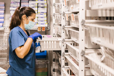 Nurse wearing protective face mask checking inventory at hospital - MMPF00452