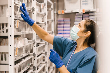 Nurse wearing face mask checking inventory at hospital - MMPF00453
