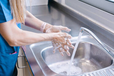 Nurse washing hands in sink at hospital - MMPF00456