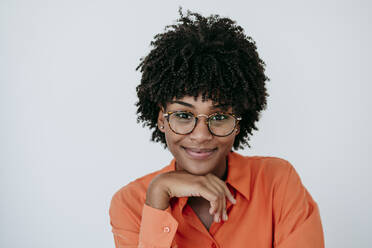 Smiling businesswoman with hand on chin in front of white wall - EBBF06872