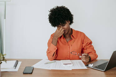 Tired businesswoman sitting at desk in home office - EBBF06877