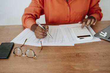 Businesswoman calculating financial bills at desk - EBBF06878