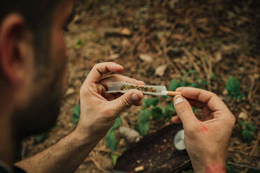 Junger Mann bereitet einen Marihuana-Joint im Wald vor - ACPF01519