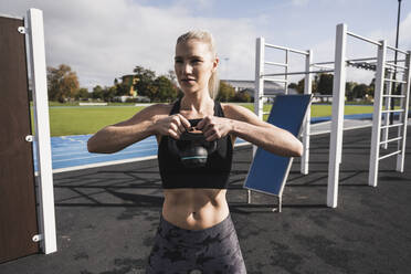 Sportler beim Training mit der Kettlebell an einem sonnigen Tag - UUF27733