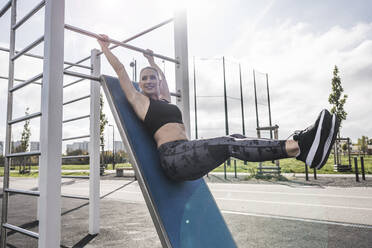 Smiling athlete practicing on horizontal bar - UUF27747