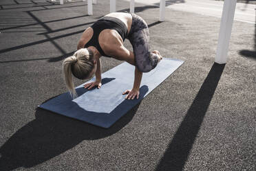 Junge Sportlerin übt Krähen-Yoga-Pose auf Übungsmatte - UUF27756