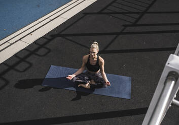 Young sportswoman meditating on exercise mat - UUF27759