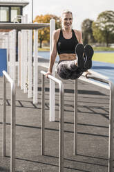 Smiling athlete exercising on horizontal bar - UUF27765