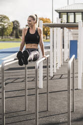 Smiling young athlete exercising on horizontal bar - UUF27767