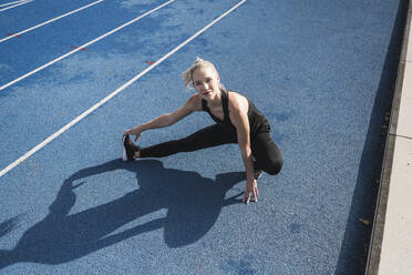 Sportswoman doing warm up exercise on track - UUF27787