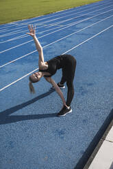 Sportswoman doing stretching exercise on track - UUF27788