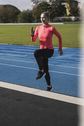 Sportswoman doing warm up exercise on running track - UUF27803