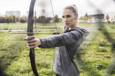 Selbstbewusste Sportlerin beim Bogenschießen auf der Wiese - UUF27809