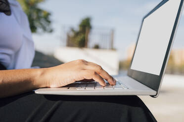 Hand of woman using laptop on sunny day - MEUF08345