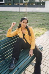 Confident young woman sitting on park bench - MEUF08390