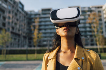 Junge Frau trägt Virtual-Reality-Simulator an einem sonnigen Tag - MEUF08404