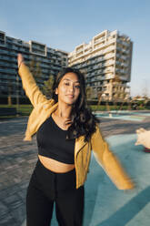 Carefree young woman with arms outstretched enjoying at playground - MEUF08411