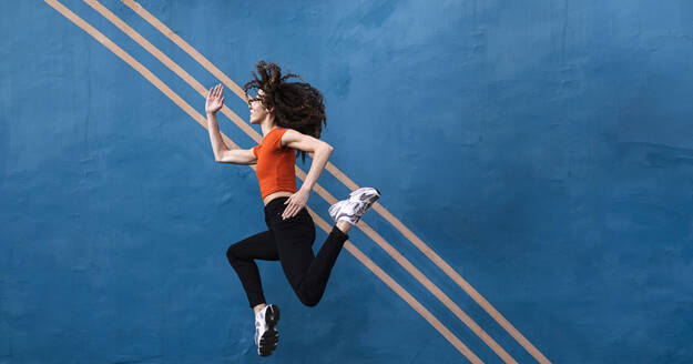 Frau springt vor die blaue Wand - AMWF00988