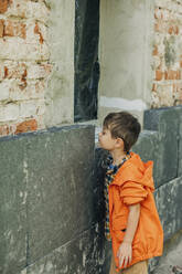 Boy looking at installed polystyrene on wall - VSNF00094