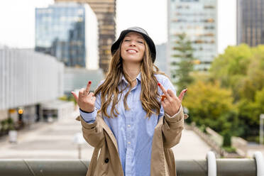 Happy businesswoman showing middle fingers in front of railing - DLTSF03388