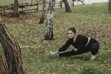 Plus sized Frau tun Stretching Übung im Park - JBUF00089