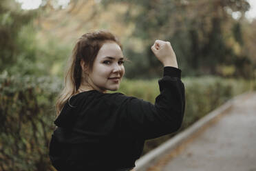 Lächelnde junge Frau beim Muskeltraining im Park - JBUF00114