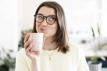 Bored businesswoman holding coffee cup in office - JOSEF14659