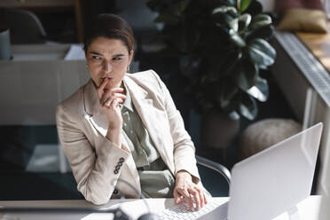 Thoughtful businesswoman with laptop at desk in office - JOSEF14689