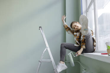 Germany, Cologne, Mature woman balancing on ladder during painting gable  roof stock photo