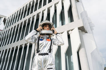 Astronaut wearing space helmet in front of building - DAMF01106