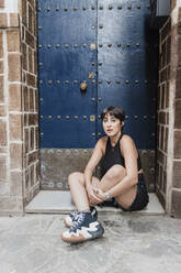 Junge Frau sitzt vor der Tür - JRVF03167