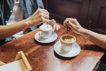 Die Hände eines jungen Paares rühren in einem Café Kaffee um - JRVF03194