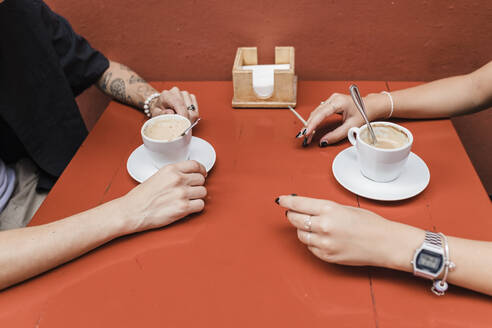 Hand of woman holding marijuana joint cigarette with man at sidewalk cafe - JRVF03198