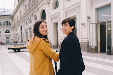 Smiling young woman with friend at urban building - MMPF00515