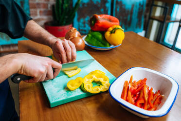 Crop anonymen Koch Schneiden reifen Paprika auf Schneidebrett beim Kochen in der modernen Küche - ADSF40235