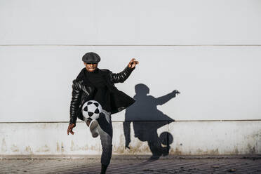 Schwarzer Mann kickt Ball auf der Straße - ADSF40266