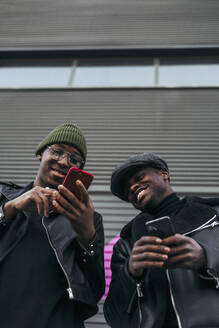 Schwarze Freunde benutzen Smartphones auf der Straße - ADSF40283