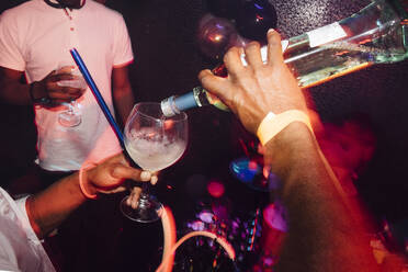 Von oben anonymer schwarzer Barkeeper, der ein Glas mit Spirituosen in einen Becher füllt, während er einen Cocktail auf einer Party in einem Nachtclub zubereitet - ADSF40292