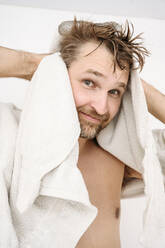 Smiling man drying hair with towel at home - EYAF02317