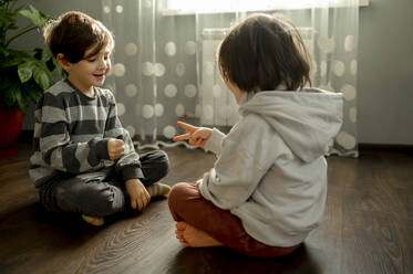 Brüder spielen Stein-Papier-Schere auf dem Boden zu Hause - ANAF00496