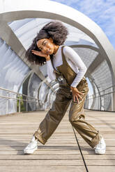 Junge Frau tanzt auf öffentlicher Brücke - DLTSF03424
