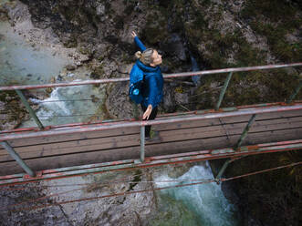 Österreich, Niederösterreich, Annaberg, Drohnenaufnahme einer Wanderin, die mit erhobenen Armen auf einer Brücke über den Otscherbach steht - HMEF01433