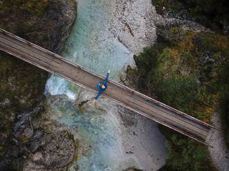 Österreich, Niederösterreich, Annaberg, Drohnenaufnahme einer Wanderin, die mit erhobenen Armen auf einer Brücke über den Otscherbach steht - HMEF01435