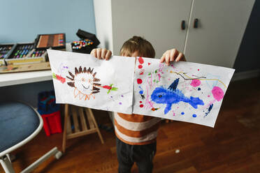 Boy showing drawing in bedroom at home - EYAF02337