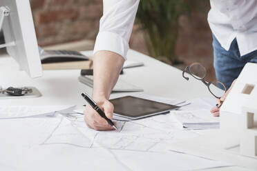 Hand eines Architekten, der mit einem Stift am Schreibtisch im Büro auf Papier schreibt - DHEF00657